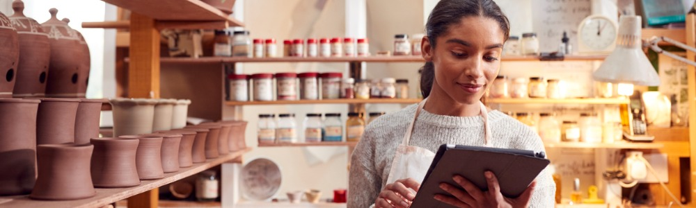 mujer joven con tablet  manejando tienda de cerámica desde su página web