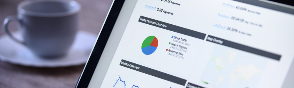 mesa con café y pantalla de computador con gráficas y datos de mercadeo digital