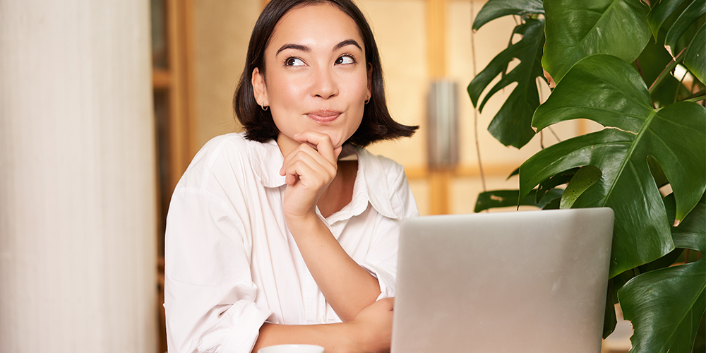 mujer emprendedora joven pensando sentada frente a computador