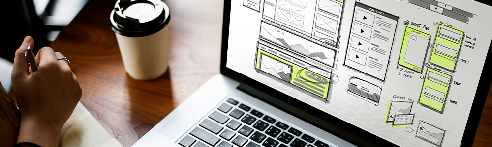 manos de mujer frente a pantalla de computador con wireframes de página web
