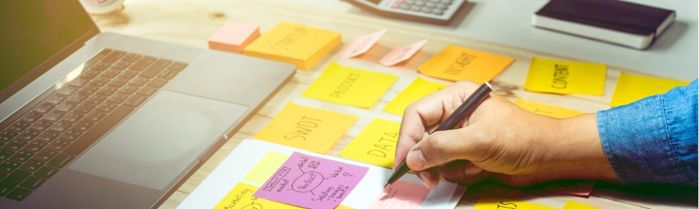 hombre emprendedor en escritorio con computador y post it notes planeando contenidos para redes sociales